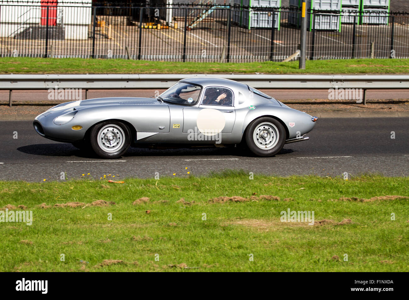 Panning a classic Silver 1960`s E-Type Jaguar sports car travelling along the Kingsway Dual Carriageway in Dundee, UK Stock Photo